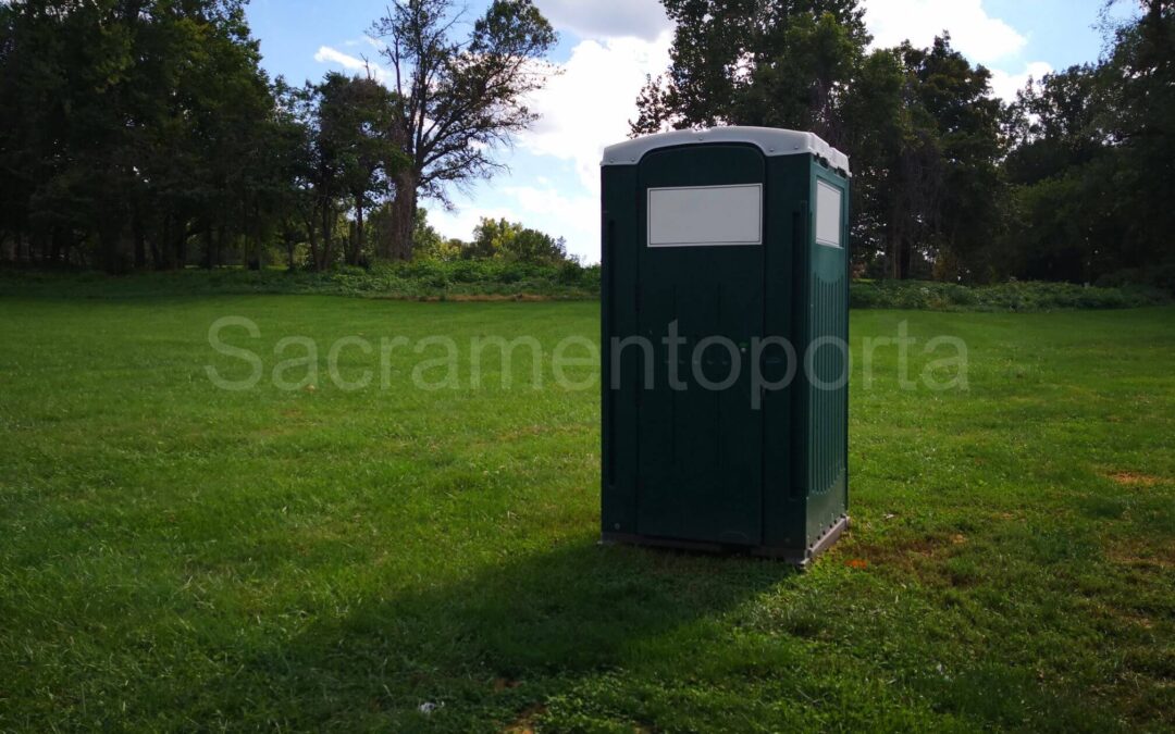 A portable toilet in a park surrounded by trees. Renting Versus Buying A Portable Potty